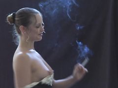 Сексуальная курящая девушка рассматривает себя в зеркале