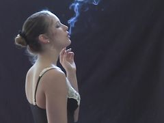 Сексуальная курящая девушка рассматривает себя в зеркале