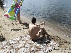 Парочка молодых нудистов загорают голышом на пустынном пляже