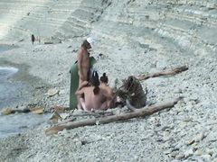 Обнаженные мужики и девочки отдыхают на каменистом пляже